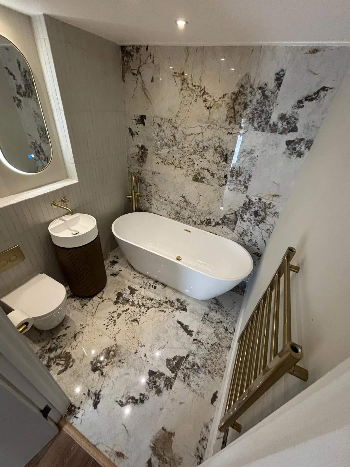 The same Hornchurch bathroom after full renovation by Bridgerose, with marble-effect tiling and a freestanding bath