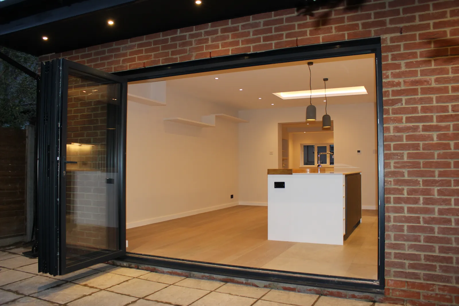 Exterior of the new brick extension with black bi-fold doors open onto the garden