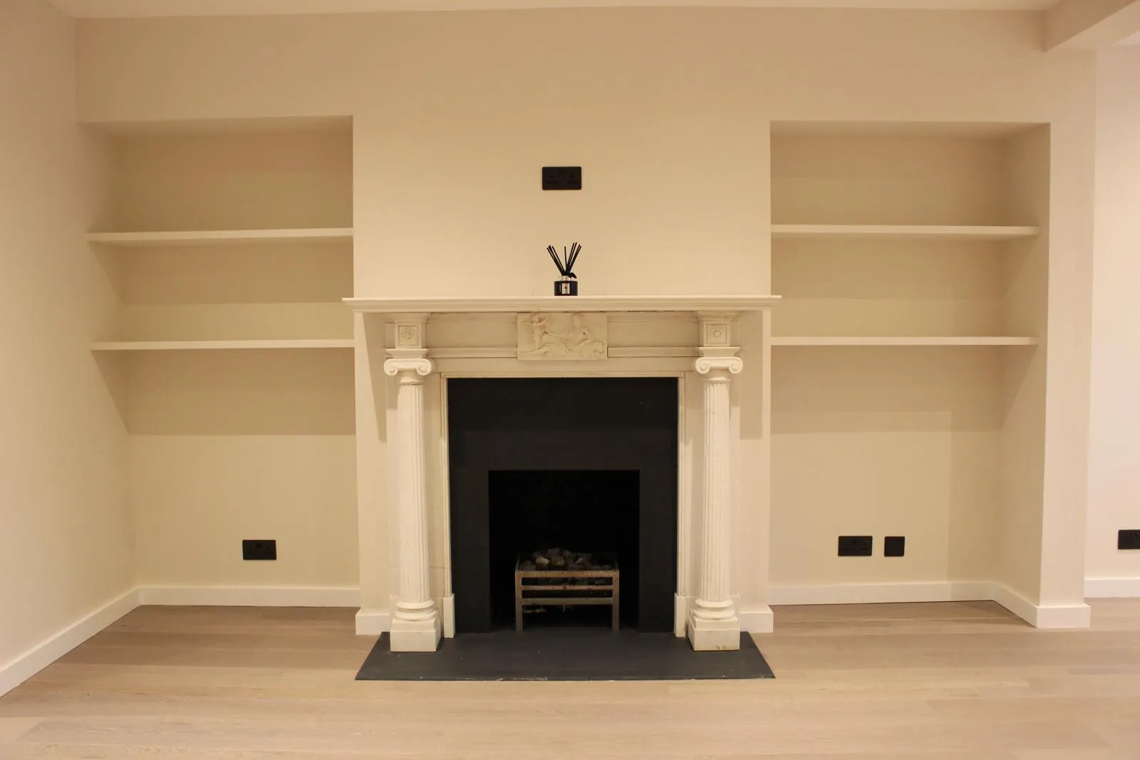 Bespoke white ornamental fireplace with fitted alcove shelving