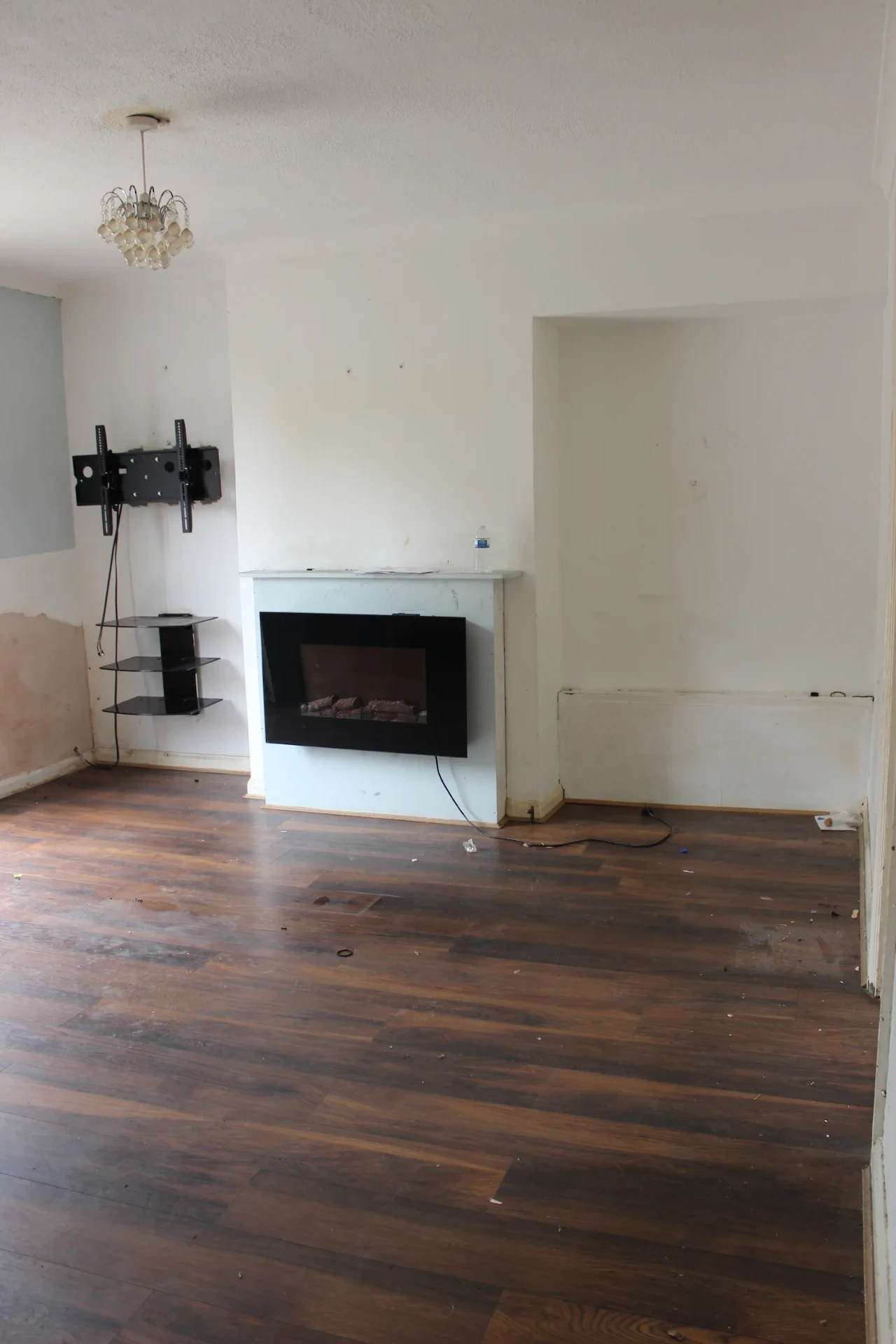Empty RM6 living room with dark timber floorboards and bare walls before renovation