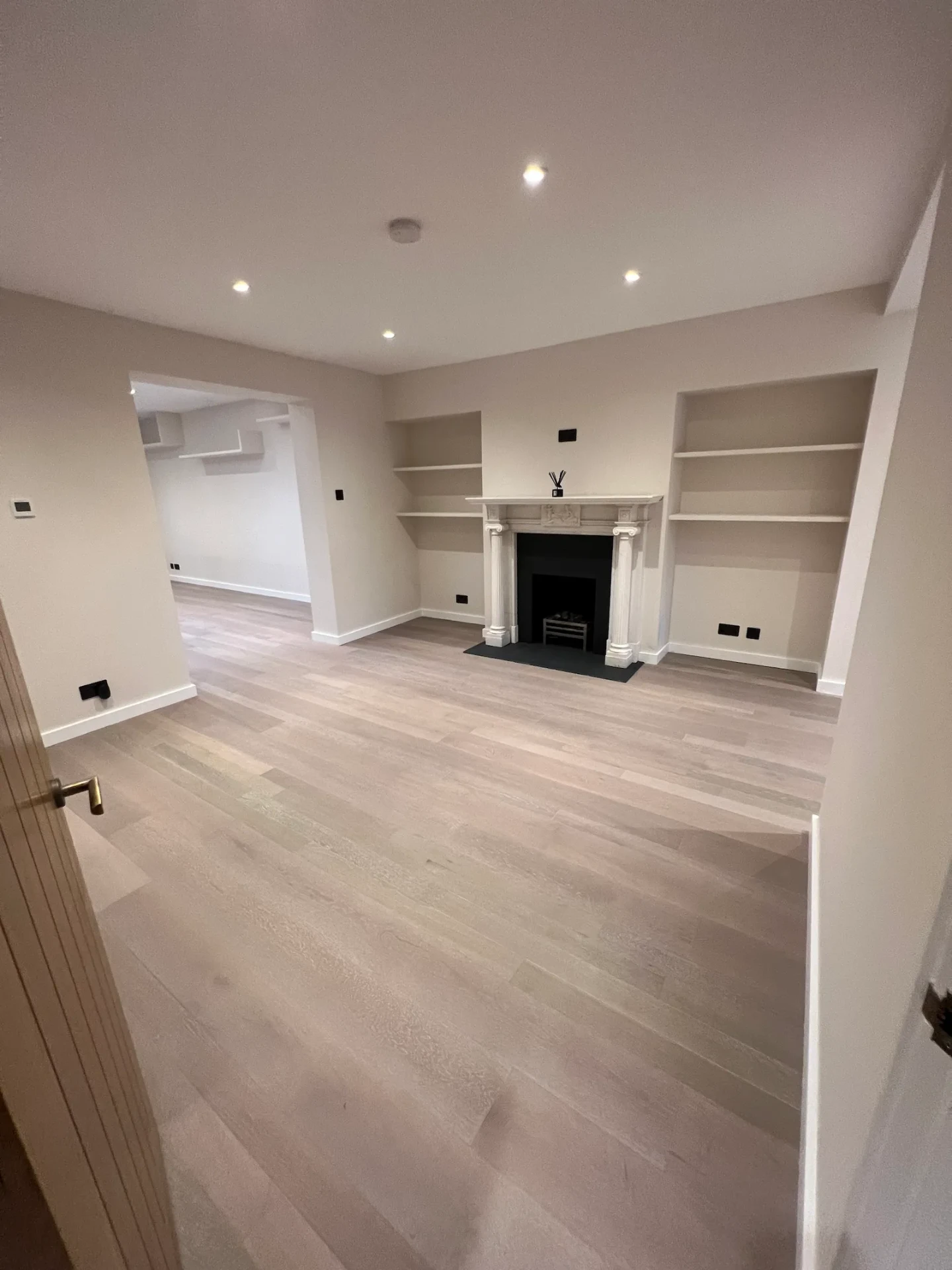 Living room with light oak flooring, white walls and new skirting and joinery