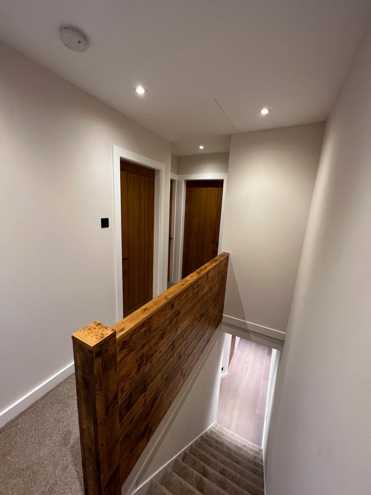 Upstairs landing with timber-capped banister and newly hung doors