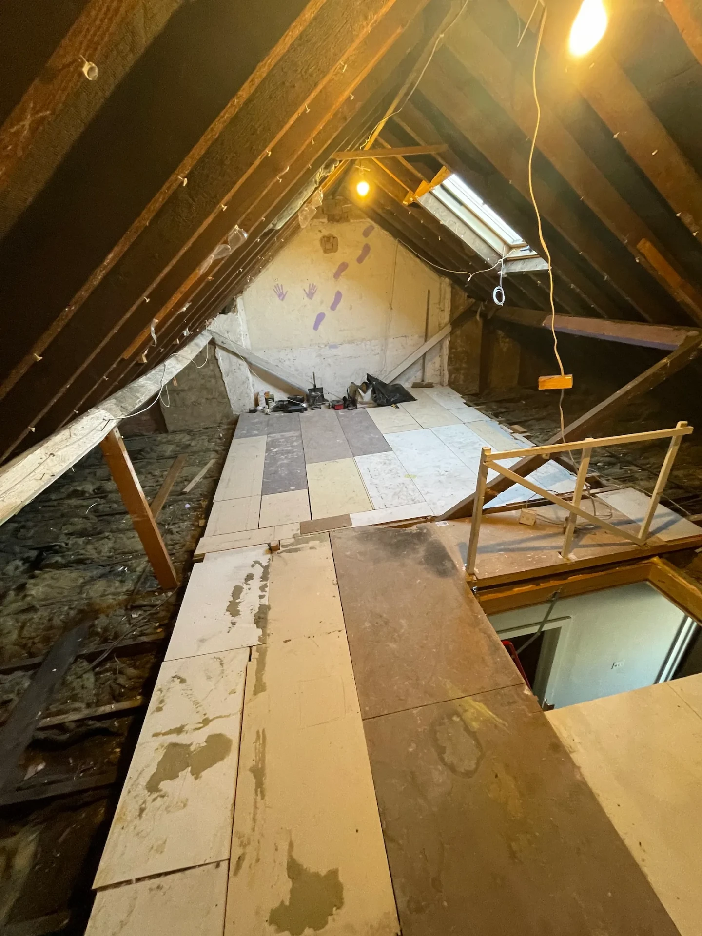 Bare Romford loft space with exposed rafters and dust sheets before conversion