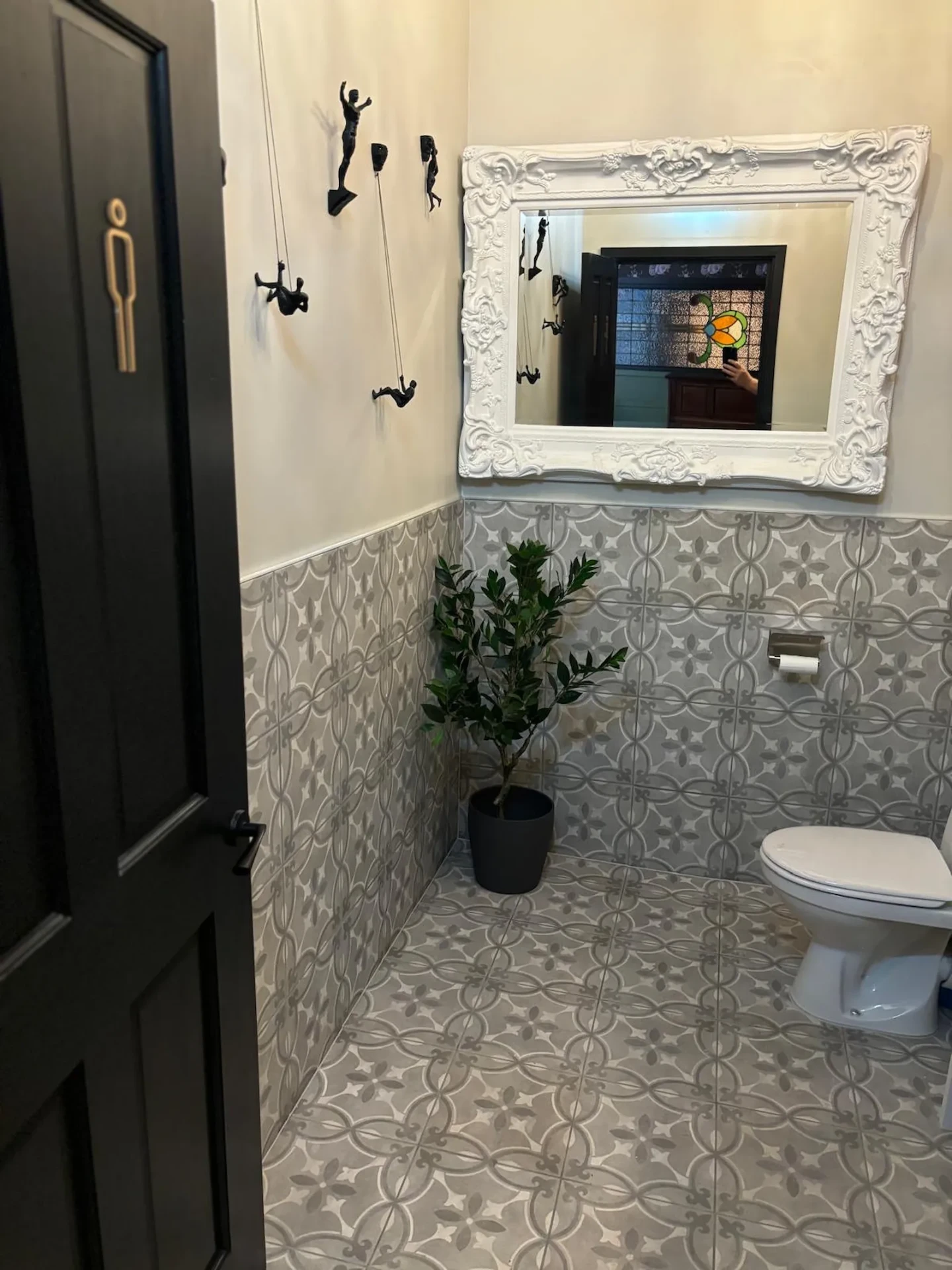 Customer WC finished in patterned grey tiling with a large ornate mirror