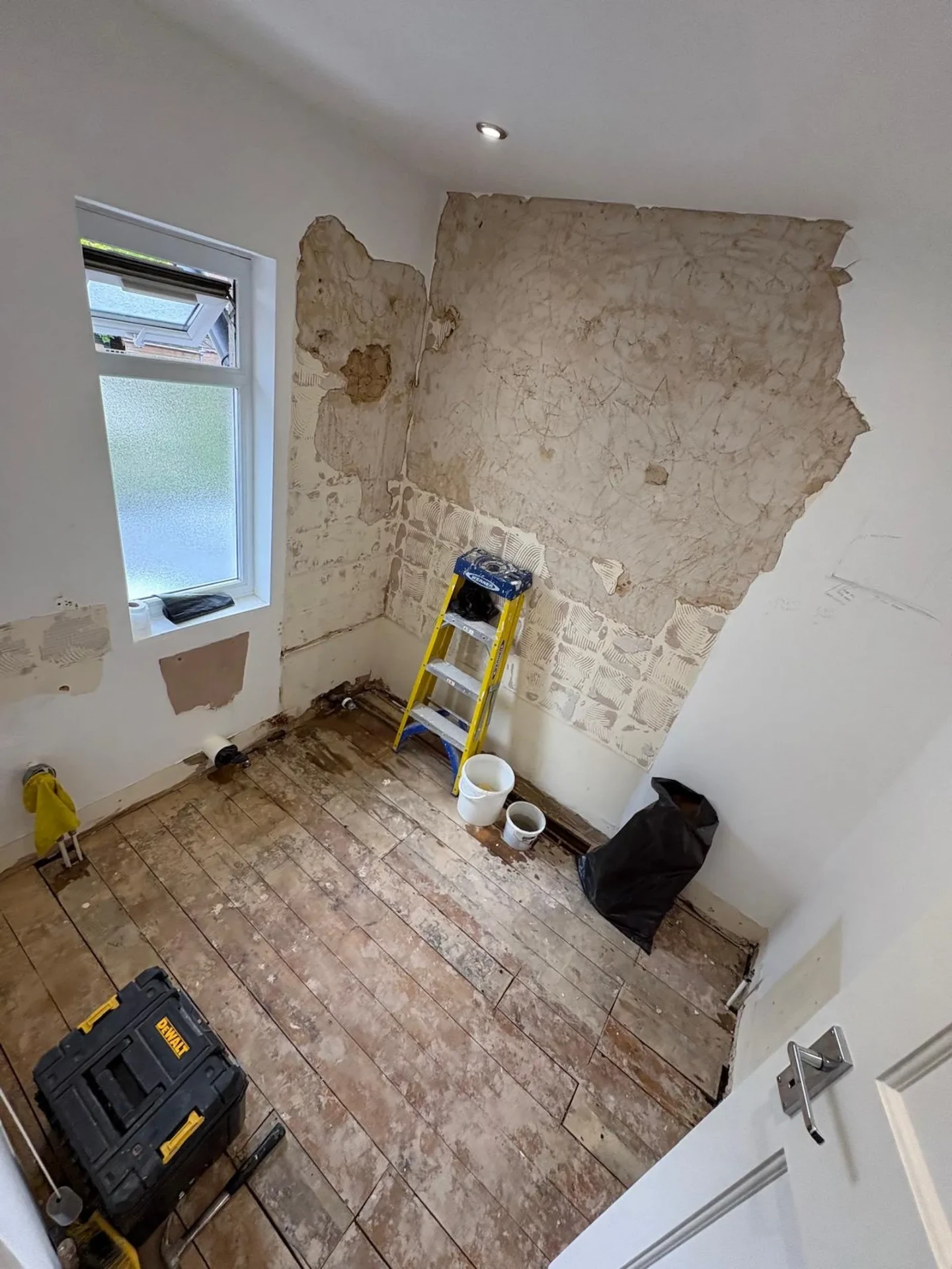 Stripped bathroom in Upminster with exposed floorboards and bare plaster before renovation